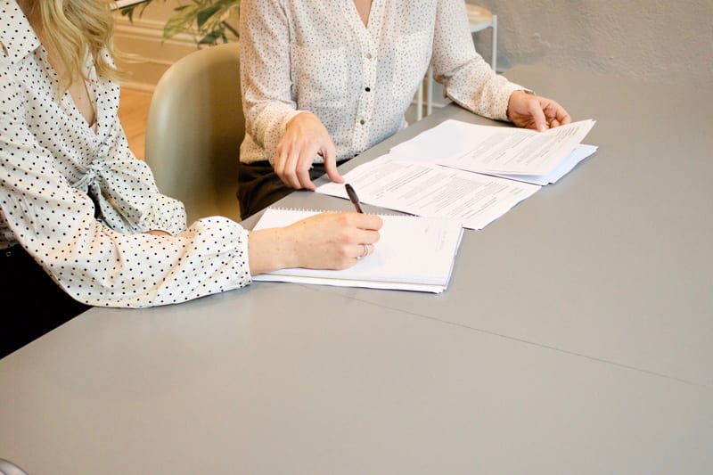 Photo of two women signing a document